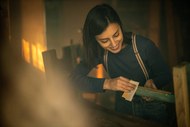 istock Young smiling female carpenter working with emery in workshop 1289630507