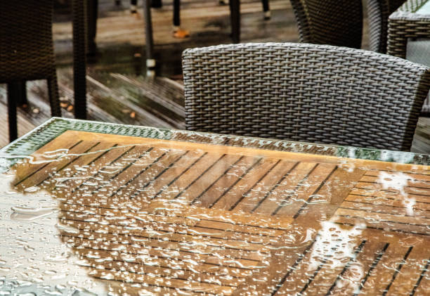 Street cafe on rainy day with raindrops on tables and chairs
