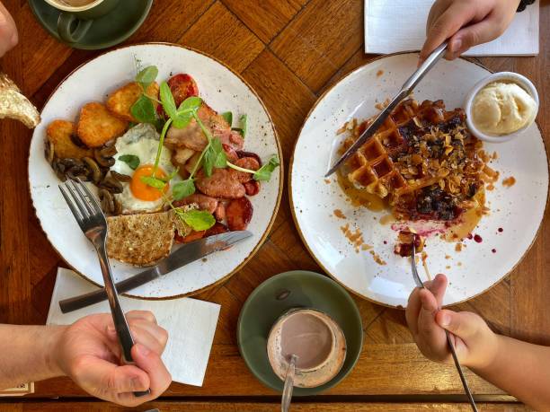 istock Top View Breakfast Waffle and Bacon and Egg with Toast  for two people with cropped hands. 1289648104