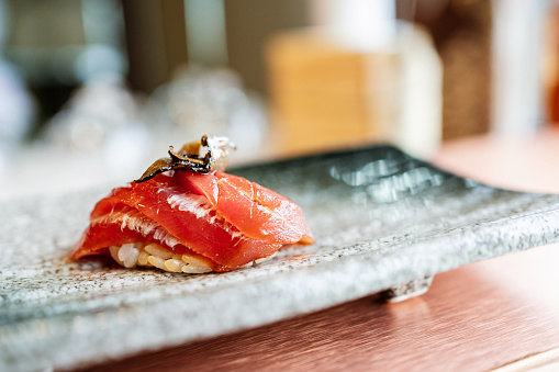 Close up of nigiri sushi with salmon, tuna, prawn in a take away container.\nSake nigiri, majuro nigiri, ebi nigiri.