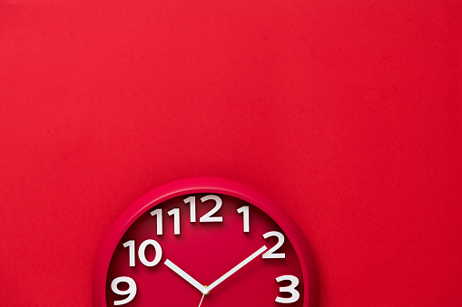 Red wall clock on red background.