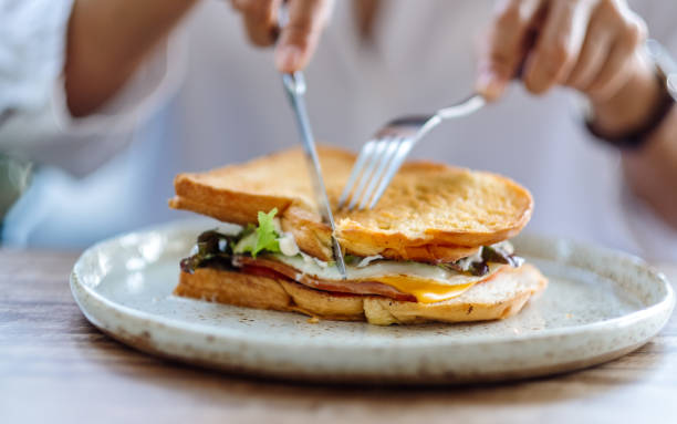 istock a woman eating ham cheese sandwich 1289653770