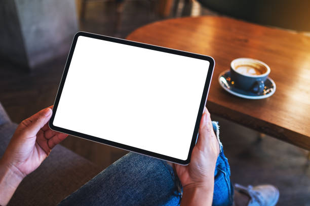 istock a woman holding digital tablet with blank white desktop screen with coffee cup on wooden table 1289653787