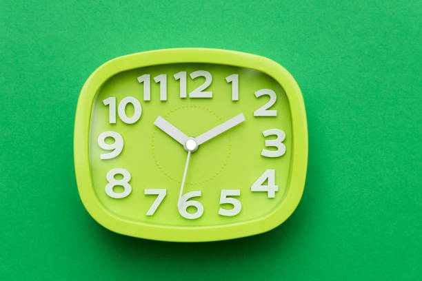 istock Modern alarm clock on green background 1289660117