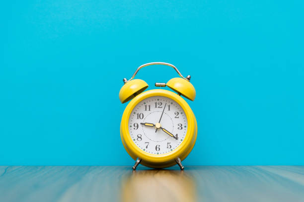 istock Yellow alarm clock on the wooden table 1289660119