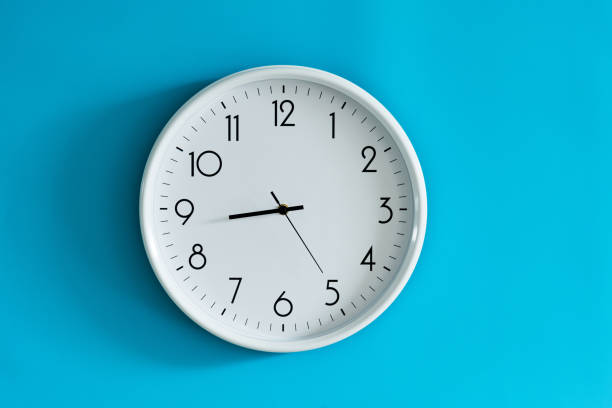orologio da parete bianco su sfondo blu - deadline time clock urgency foto e immagini stock