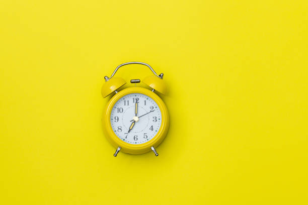 istock Yellow alarm clock on yellow background 1289661786