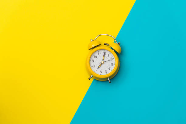 istock Yellow alarm clock on colored background 1289662524