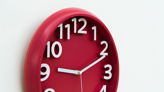 Red wall clock on white background.
