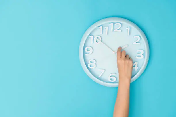 Photo of Human hand adjusting the hour clock