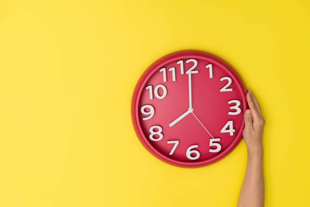 istock Human hand holding a clock on yellow background 1289663477