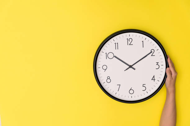 istock Human hand holding a clock on yellow background 1289663478
