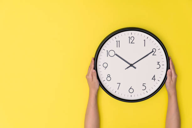 istock Human hand holding a clock on yellow background 1289665168