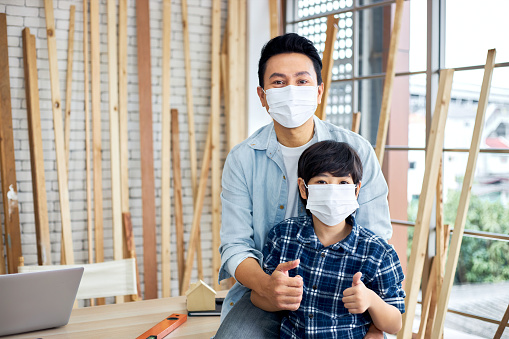 A carpenter father sits with his son at his desk.