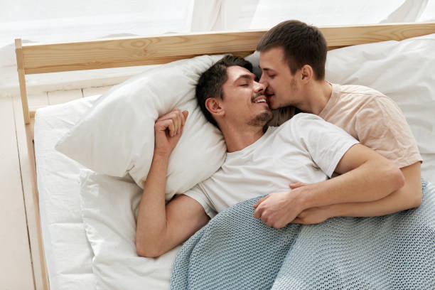 glückliches schwules paar liegt zu hause auf dem bett - men sensuality photography high angle view stock-fotos und bilder
