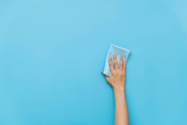 istock Woman hand cleaning blue wall with rag 1289666107