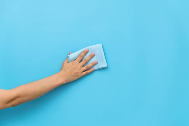 istock Woman hand cleaning blue wall with rag 1289666108