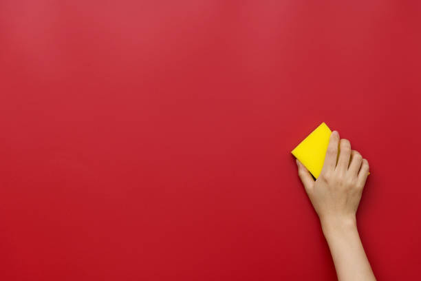 istock Woman hand cleaning red wall with sponge 1289666781