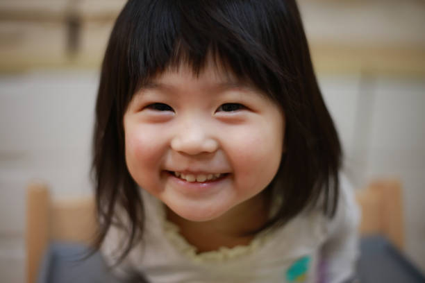 Cheerful girl having fun while peeking behind the table at home. Copy space.
