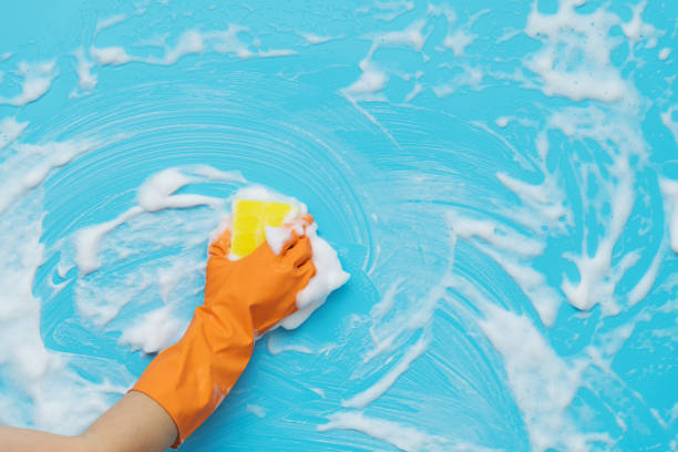 istock Woman hand cleaning blue wall with sponge 1289669299