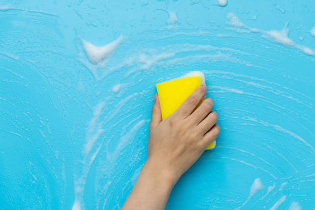 istock Woman hand cleaning blue wall with sponge 1289670060