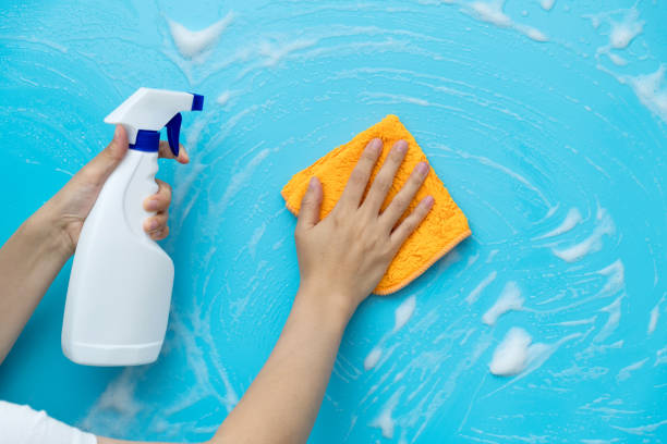 istock Woman hand cleaning blue wall with rag and spray bottle 1289670127