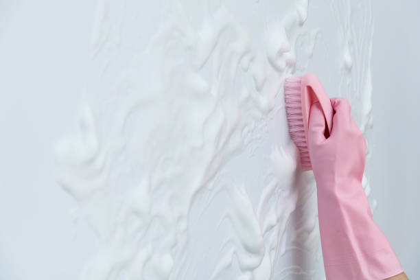 istock Woman hand cleaning blue wall with brush 1289670955