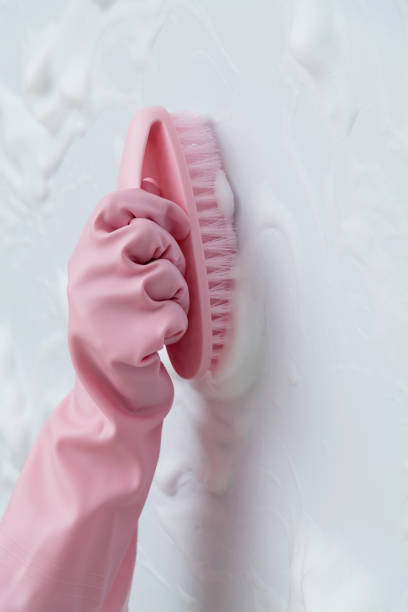 Woman hand cleaning blue wall with brush.