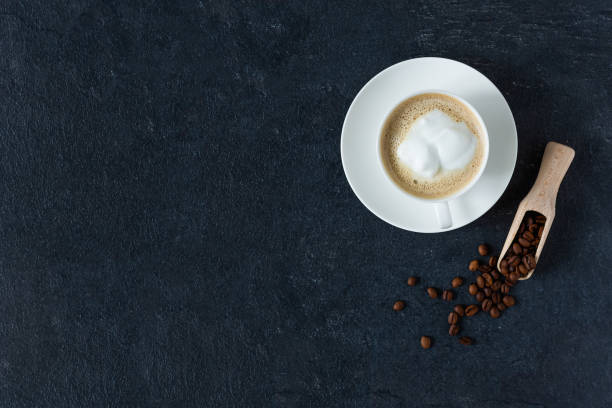 istock Coffee cup with milk and roasted coffee beans on black background top view. 1289674136