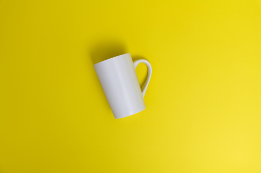 White mug on yellow background.