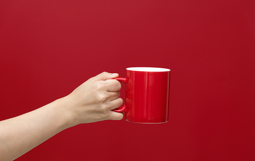 Human hand holding a red mug.