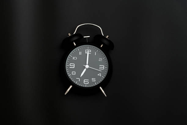 istock Black alarm clock on black background 1289677057