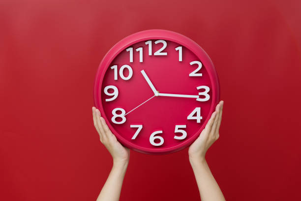 main humaine retenant une horloge sur le fond rouge - clock time clock hand urgency photos et images de collection