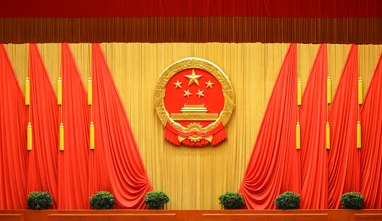 National emblem of the People's Republic of China and Red flags at the Great Hall of the People in Beijing, China