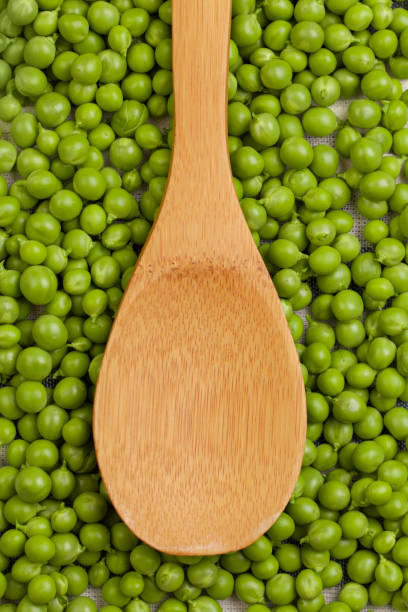 istock Green peas in wooden spoon, top view 1289681074