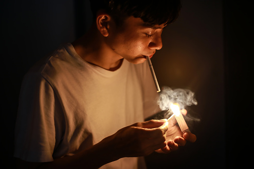 A man who ignites a cigarette with a match