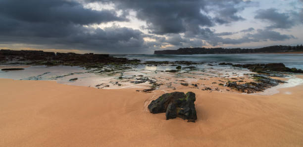 Grey clouds and rocky foreground overcast panorama sunrise at the beach Overcast sunrise seascape at North Avoca Beach on the Central Coast, NSW, Australia. avoca beach photos stock pictures, royalty-free photos & images