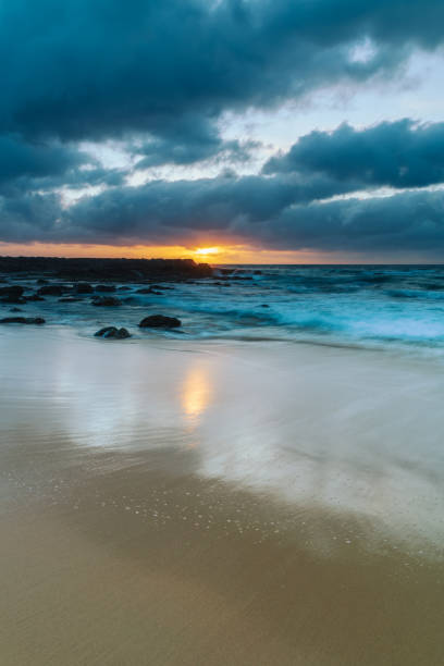 Grey clouds and rocky foreground overcast sunrise at the beach