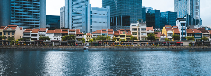 Boat Quay next to the Singapore River is an old area of houses in Singapore. Behind them the high office skyscraper buildings in the financial districts are rising to the sky.