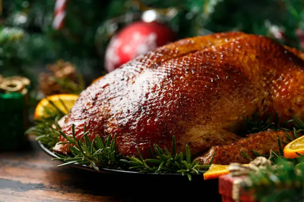Photo of Roasted Christmas duck with decoration, gifts, green tree branch on wooden rustic table
