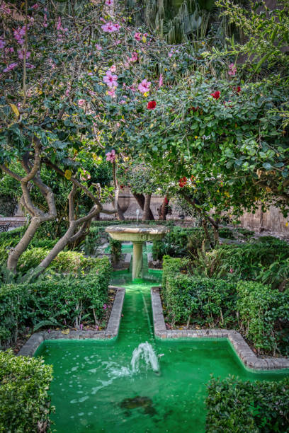 Lush gardens decorated with ancient fountains in a public square next to the Cathedral of Malaga, Costa del Sol, Andalusia, Spain