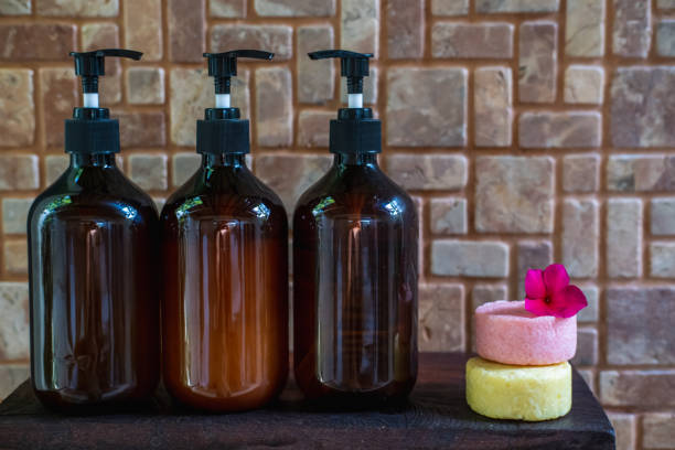 Eco friendly colorful solid shampoo bars, conditioner or soap with glass dispenser bottles in bathroom shelf. Reusable organic home products. Zero waste and sustainable plastic free lifestyle concept