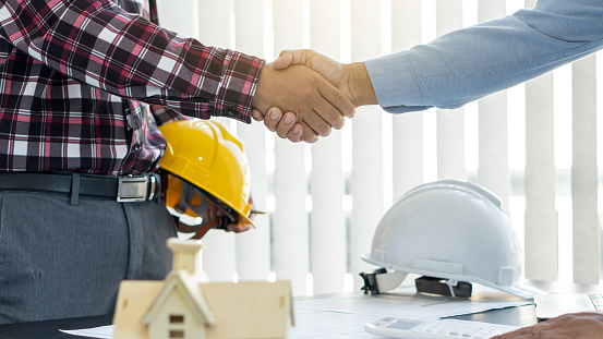 The architect and engineer shook hands while working as a team and cooperation concept after completing the agreement in the office.