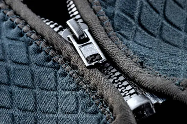 Macro shot of a half-closed, plastic zipper in a modern blue garment.
