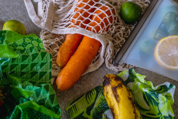 Fruits and vegetables packed in environmentally safe beeswax wraps, reusable ziplock and mesh tote bag. Eco-friendly kitchen products. Zero waste sustainable plastic free lifestyle