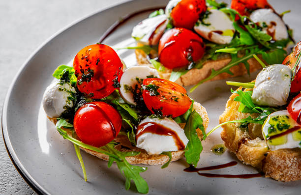 bruschetta italiana con tomates tostados, queso mozzarella, vinagre balsámico y hierbas en el plato - caprese salad salad restaurant vinegar fotografías e imágenes de stock