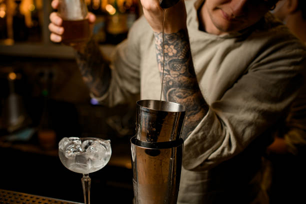 istock Man bartender gently pours drink from metal jigger into shaker on bar counter 1289703327