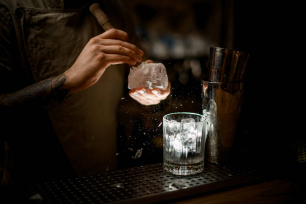 istock bartender holds ice and accurate breaks off pieces from it and glasses stands nearby 1289703377