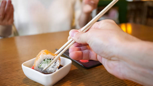 istock Male hand dipping roll with chopsticks in soy sauce 1289703480