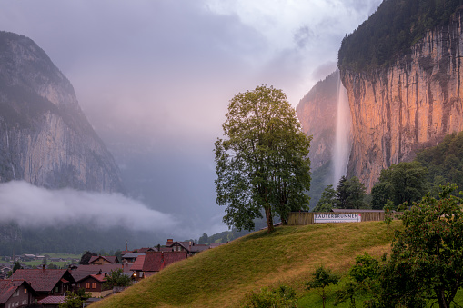 Lauterbrunnen, Switzerland - July 2, 2020: A valley view of the alpine village in Bernese Highlands region of Switzerland with the Staubbach Fall in the background
